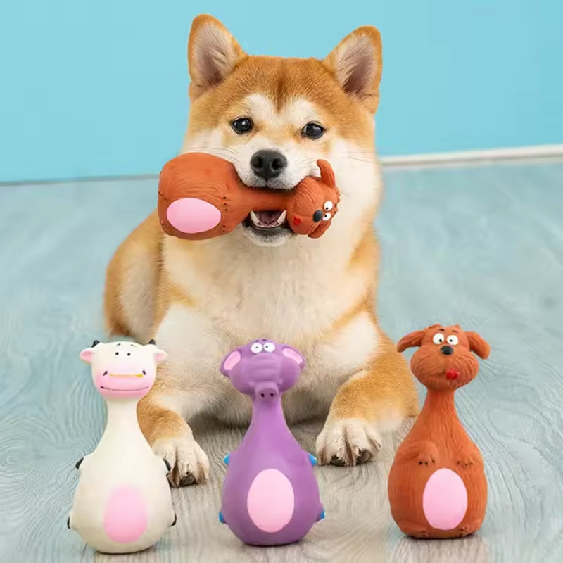 Shiba Inu holding one latex chew toy with three more animal-shaped toys beside it